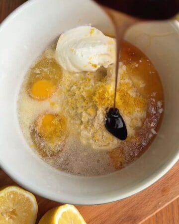 Mixing eggs, sugar, and vanilla for baking with syrup being poured.