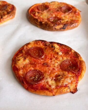 Close-up of mini pepperoni pizzas with melted cheese and crispy crusts.