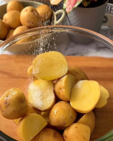 Yellow potatoes being washed in a glass bowl for cooking or preparation.