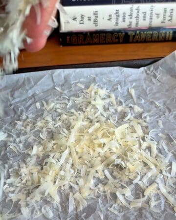 Freshly shredded cheese on parchment paper for cooking or baking.
