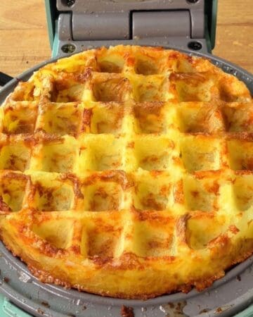 Golden waffle breakfast potato with melted cheese and crispy edges.