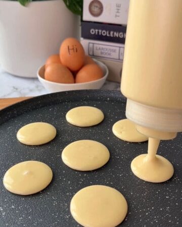 Pancake batter being poured onto a skillet for cooking.