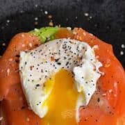 Smoked salmon, poached egg, and green onion on a sweet potato waffle with black sesame seeds.